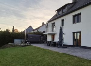 ein weißes Haus mit einer Terrasse und einer Liegewiese in der Unterkunft Ferienhaus Waldzauber-Winterberg in Winterberg