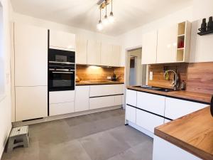 eine Küche mit weißen Schränken und schwarzen Geräten in der Unterkunft Ferienhaus Waldzauber-Winterberg in Winterberg