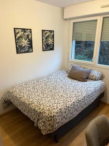 a bed in a bedroom with two pictures on the wall at Appartement Paisible au Vert in Saint-Ouen