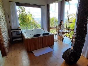 オウロ・プレットにあるSuíte Ad`vinhoの女性がバスタブ付きの部屋に座っている