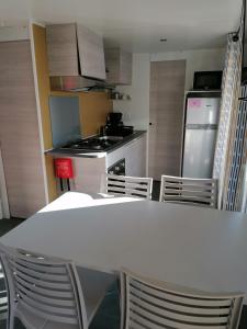 a kitchen with a white table and chairs in it at MOBIl HOME LE NARBONNAIS in Valras-Plage