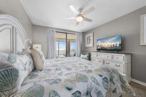 a bedroom with a bed with a ceiling fan and a television at Bluewater Vacation Rentals in Orange Beach