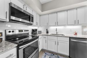 a kitchen with white cabinets and stainless steel appliances at Bluewater Vacation Rentals in Orange Beach