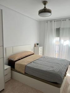a white bedroom with a bed and a window at Ático con vista mar a 300m de la playa para 6 personas in Garrucha