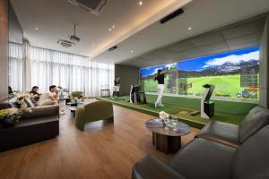 a living room with a large screen with a golf game at The Metropole Opera Residence by KayStay in Ho Chi Minh City