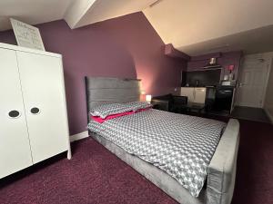 Un dormitorio con una cama y una pared morada. en Best Apartments Mcr, en Mánchester