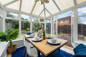 Un invernadero con una mesa y sillas de madera. en Trendy 3 Bed House, Sleeps 6, Near NEC - Airport, Parking, Contractors - Families Stay, en Sheldon