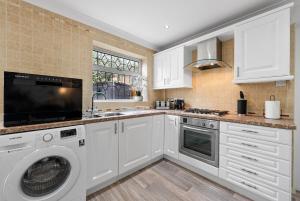 a kitchen with white cabinets and a washer and dryer at Stylish 3 Bed House, Sleeps 6, Near NEC - Airport, Parking, Contractors - Families Stay in Sheldon