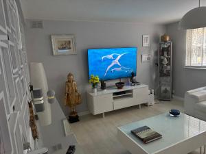 ロンドンにあるSTUNNING GARDEN APARTMENT Central Exclusive Self Catering With Free Off Road Parking By Flat & Wiffi Beautifully Secluded 3 mins From All Amenities Home Not Hotelの壁に薄型テレビが取り付けられたリビングルーム