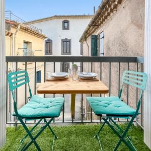 a wooden table and two chairs on a balcony at Maison charmante clim et balcon en centre ville in Marseillan