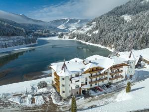 an aerial view of a hotel in the snow next to a lake at Hotel Seehof in Monguelfo