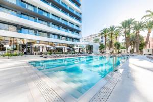 a swimming pool in front of a building at Port Alicante City & Beach in Alicante