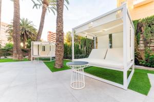 a white swing on a lawn with palm trees at Port Alicante City & Beach in Alicante