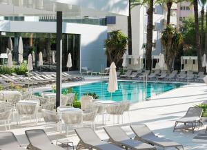 a swimming pool with chairs and tables and a hotel at Port Alicante City & Beach in Alicante
