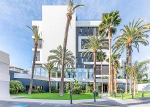 a building with palm trees in front of it at Port Alicante City & Beach in Alicante