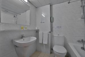 a white bathroom with a toilet and a sink at Odysseia Hotel Kapetanios in Limassol