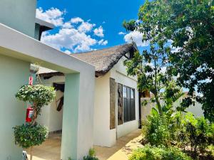 a white house with a tree in front of it at kwamapulaneng guest house in Matrooster