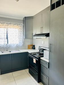 a kitchen with blue cabinets and a stove top oven at kwamapulaneng guest house in Matrooster +24 photos