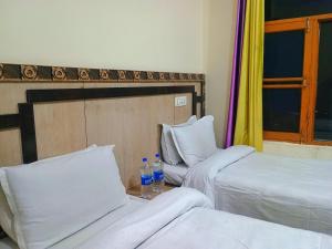 two beds in a room with two bottles of water at Verma Guest House in Dharmsala