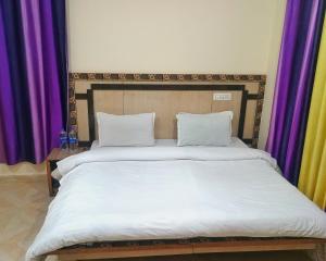 a large bed with white sheets and purple curtains at Verma Guest House in Dharmsala +7 photos