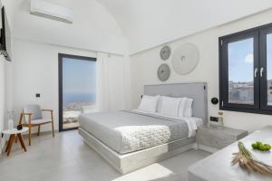 a white bedroom with a bed and some windows at Blé Suites Santorini in Imerovigli
