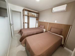 a small room with two beds and a window at Apartamento em Arraial do Cabo in Arraial do Cabo