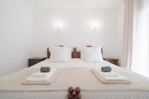 een wit bed met twee handdoeken en twee slippers erop bij 5 bedroom Beach house in Luz, Lagos in Luz +48 foto's