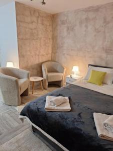 a bedroom with a large bed and a chair at Apartman Helena 2 in Lazarevac