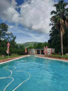 a swimming pool with blue water in front of a house at Wayside Lodge in Waterval Boven