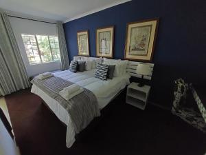 a bedroom with a large bed and a blue wall at Wayside Lodge in Waterval Boven