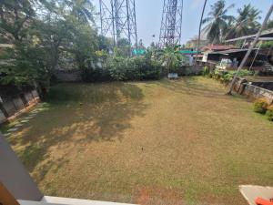 a large yard with grass and trees and a fence at Aurora-The Pool Villa in Kozhikode