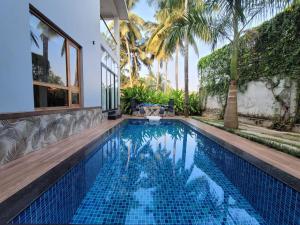a swimming pool in a villa with palm trees at Aurora-The Pool Villa in Kozhikode
