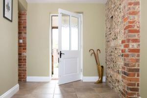 a hallway with a white door and a brick wall at Stunning Cottage in South Downs National Park in Eartham
