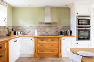 a kitchen with white cabinets and a wooden counter top at Stunning Cottage in South Downs National Park in Eartham +52 photos