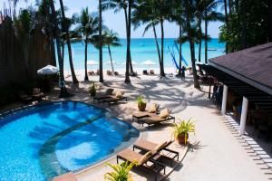 einen Pool neben einem Strand mit Palmen in der Unterkunft Microtel by Wyndham Boracay in Boracay