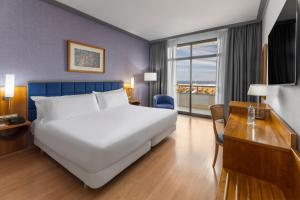a bedroom with a large white bed and a desk at Elba Vecindario Aeropuerto Business & Convention Hotel in Vecindario