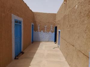 an alley with a blue door in a building at Los ojos del desierto in Merzouga +3 photos