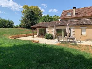 een huis met een patio met een tafel en een parasol bij Cottages Piscine Tennis 22pers in Bourrou