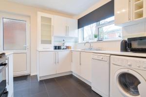 a kitchen with white cabinets and a washer and dryer at Charming & Spacious City Centre House - Perfect for Family & Contractor - Sleeps 8 in Canterbury +36 photos