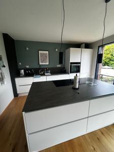 a kitchen with white cabinets and a black counter top at Modern oasis of peace with garden, top public transport in Düsseldorf