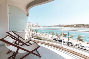 Un balcón con una silla y vistas al océano. en The Strand Luxurious Seafront Apartment, en Sliema
