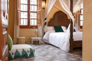a bedroom with a canopy bed and a chair at Daba Riads in Marrakech