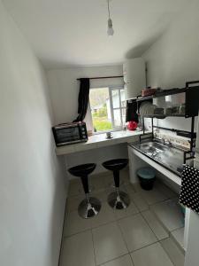 a small kitchen with two bar stools in a kitchen at Casa Doña Elsa - amoblada ideal descanso en Volcán - Jujuy in Volcán