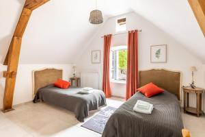 two beds in a attic room with a window at Domaine de la Garnauderie Gîte des Chênes in Sainte-Maure-de-Touraine