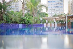 a swimming pool in a resort with trees and buildings at Odysseia Hotel Kapetanios in Limassol