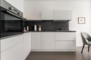 a white kitchen with white cabinets and a chair at Heart Apartment in Merano