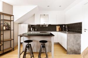 a kitchen with white cabinets and a counter with stools at The View - Tromsø City Center in Tromsø