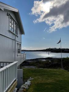 a house with a flag next to a body of water at Nordlandshus ved havet på Reine, Lofoten in Reine