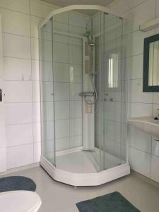 a glass shower in a bathroom with a sink at Leilighet med balkong og havutsikt på Napp. in Napp