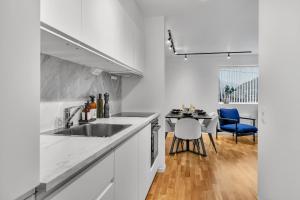 a kitchen with a sink and a table with blue chairs at Northstay - The Urban City Haven in Tromsø +19 photos